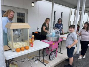 Parents helping serve popcorn and cotton candy at school Fall Festival